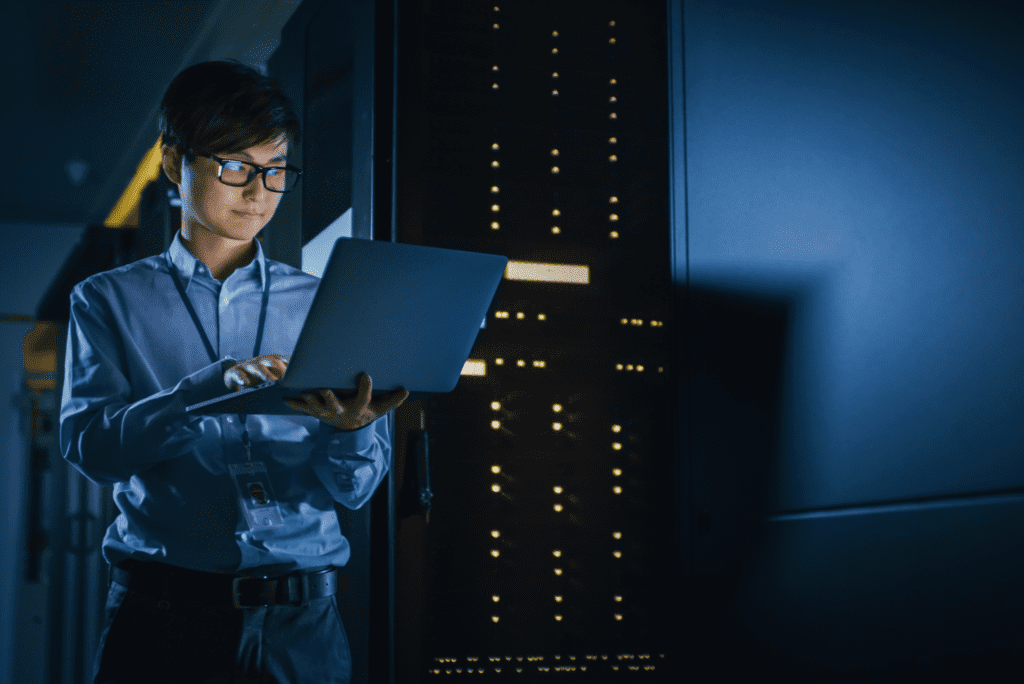 Woman looking at a laptop in a server room.